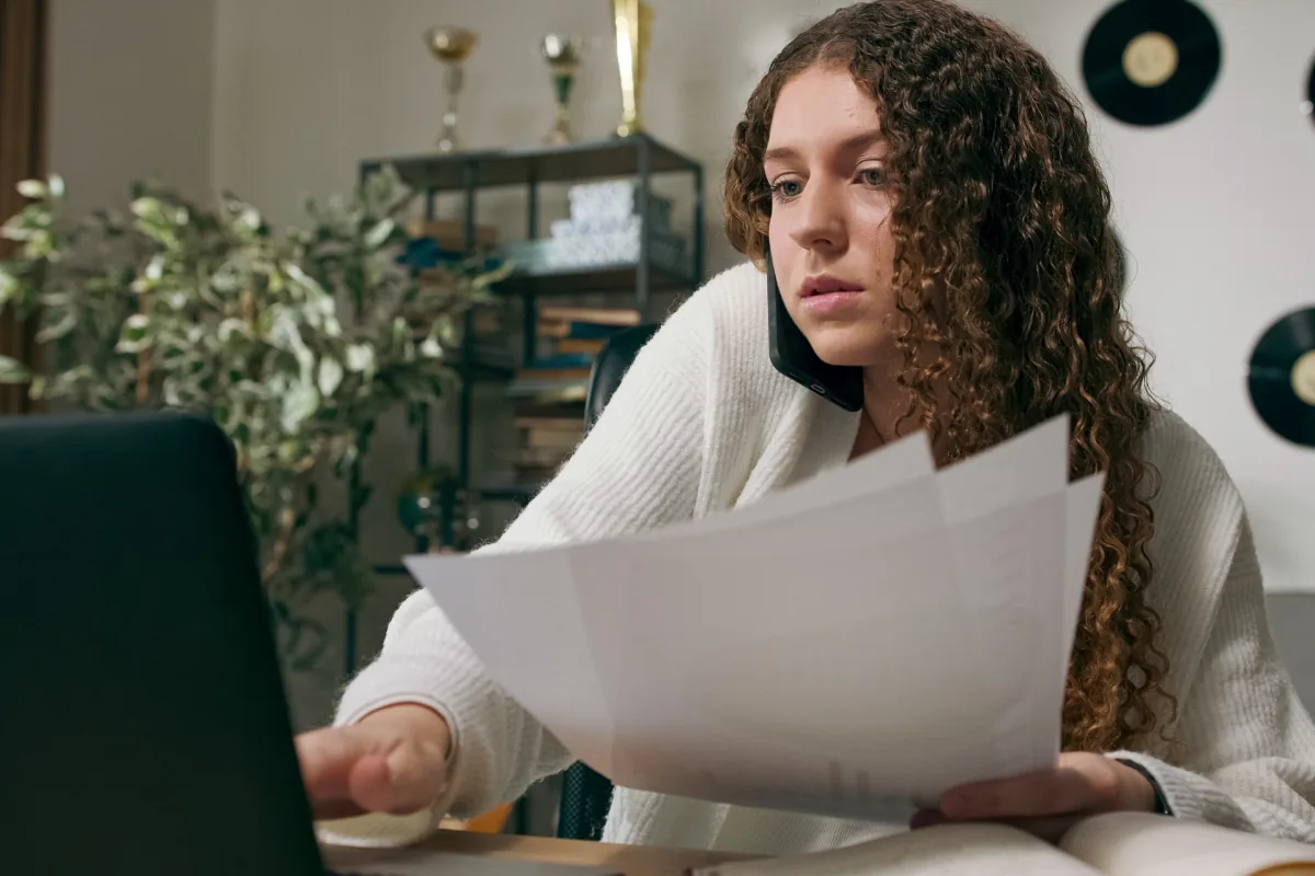 insurance-levels-of-care-how-verification-works Person reviewing insurance documents and notes while preparing to verify mental health care benefits by phone