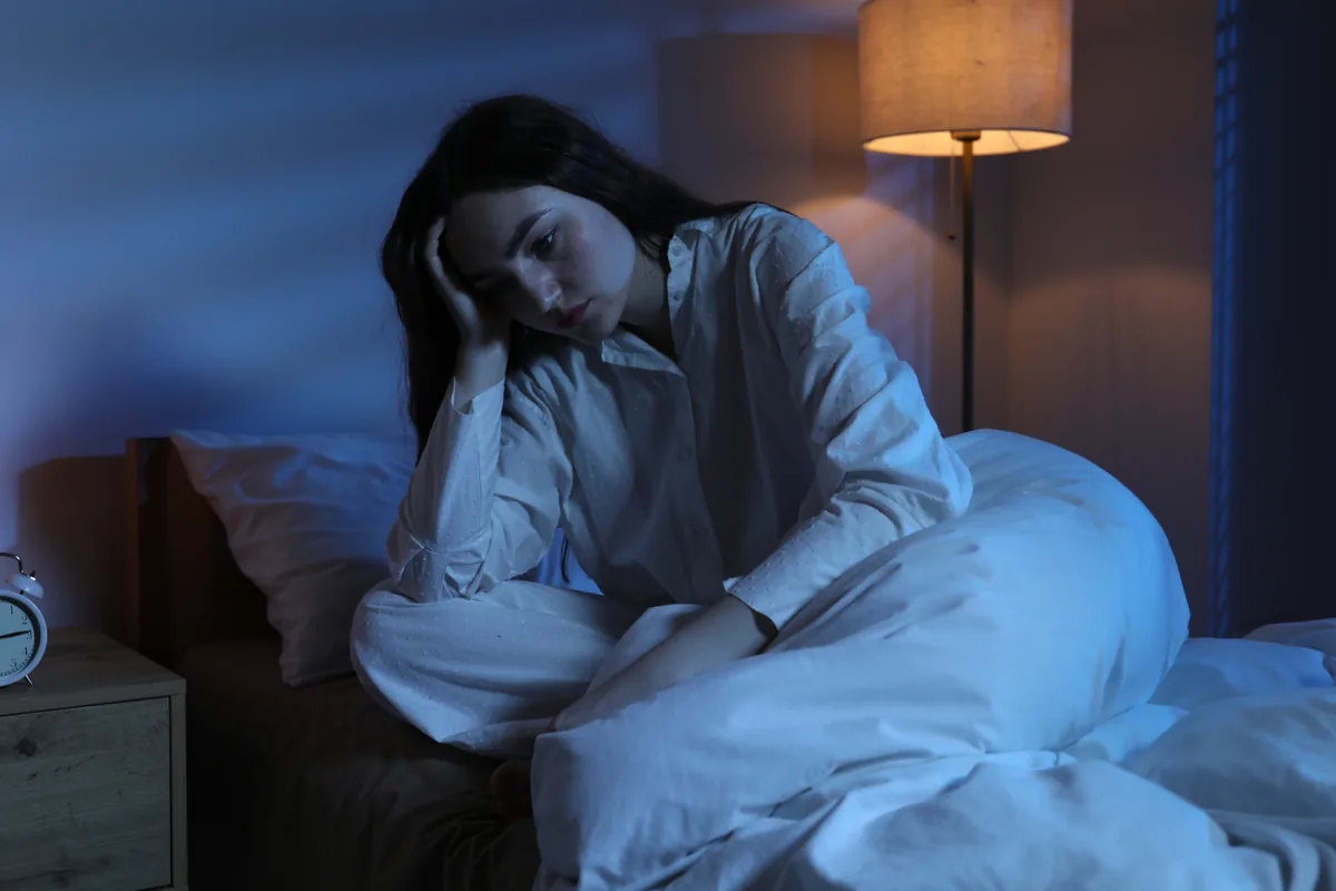 sleep-as-symptom-insomnia-signals-need-for-higher-level-of-care Person lying awake in bed at night struggling with insomnia, a possible sign of a deeper mood or anxiety condition